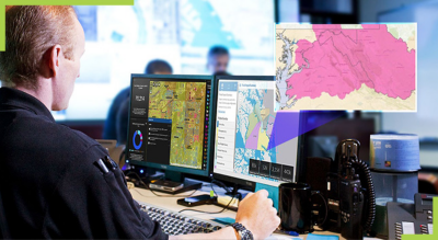 A person working on a computer with two screens in an office and a pink map overlaid