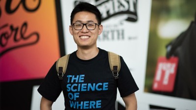 A conference attendee wearing a black shirt with The Science of Where in blue letters screenprinted on the front
