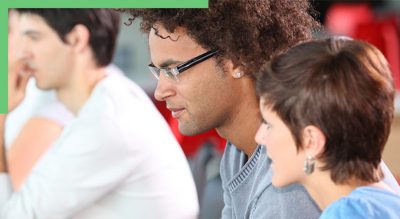  A diverse group of people seated in a classroom, engaged in discussion and learning activities.