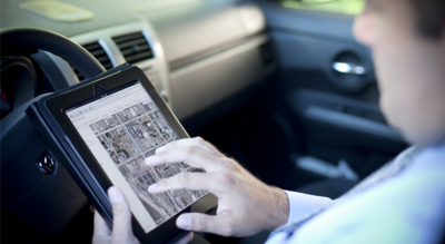 A man sitting in a car using a tablet computer